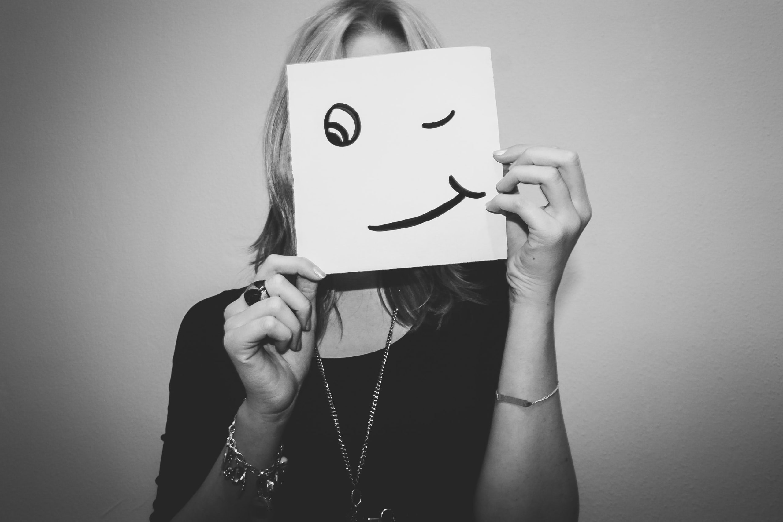 Woman holding up a smiley face card in place of face
